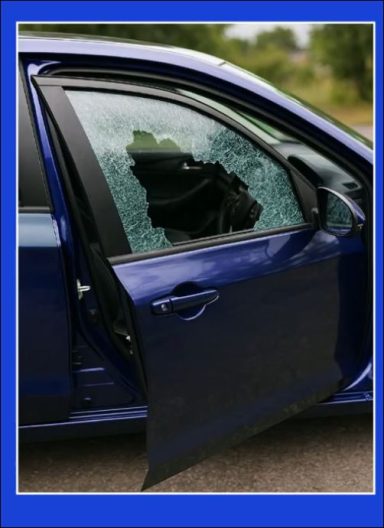 A blue car with a shattered window and an open door.